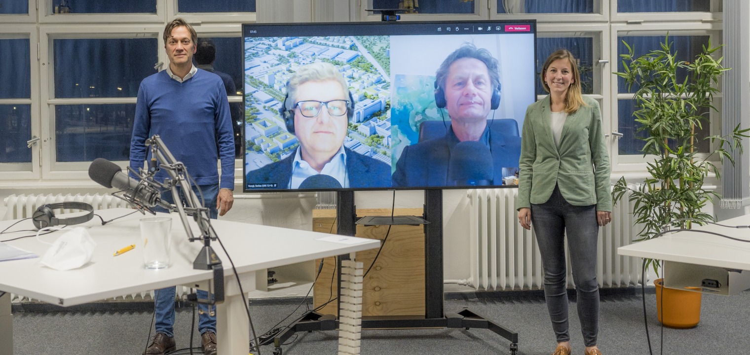 Michael Peter stands in the podcast studio, his conversation partners can be seen on a screen