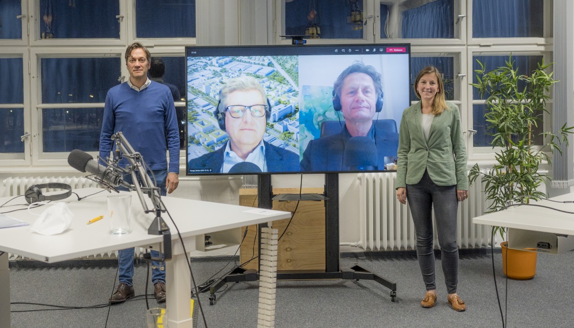 Michael Peter stands in the podcast studio, his conversation partners can be seen on a screen